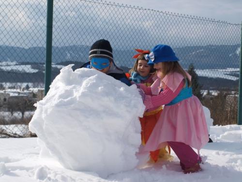 Zábava detí v&nbsp;maskách na&nbsp;snehu - stavanie snehuliakov za&nbsp;pomoci rodičov.