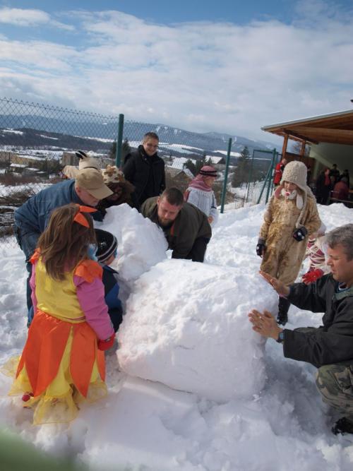 Zábava detí v&nbsp;maskách na&nbsp;snehu - stavanie snehuliakov za&nbsp;pomoci rodičov.